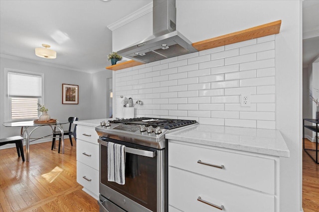 kitchen featuring light wood-style flooring, gas stove, crown molding, and wall chimney range hood