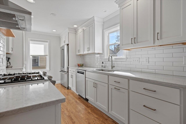 kitchen with white cabinets, ornamental molding, light wood-style floors, and stainless steel appliances