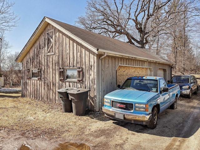 view of side of property featuring a garage, roof with shingles, and an outdoor structure