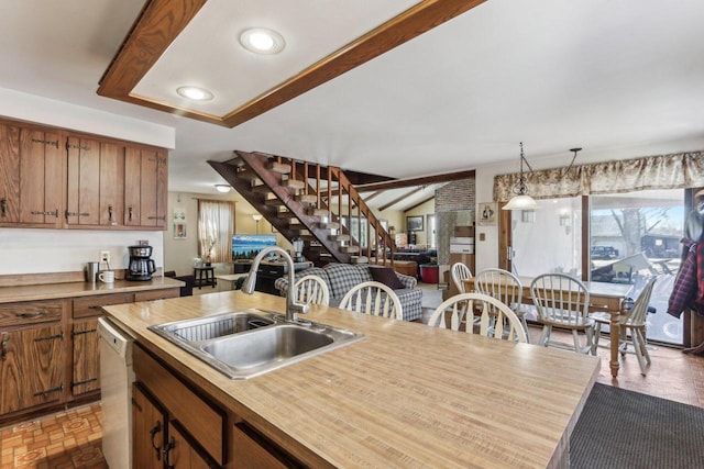 kitchen with a sink, open floor plan, light countertops, brown cabinets, and dishwasher