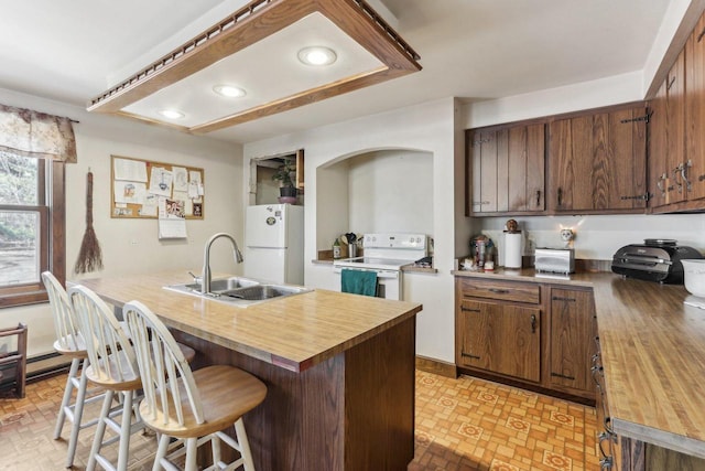 kitchen with butcher block countertops, white appliances, a sink, and a kitchen breakfast bar