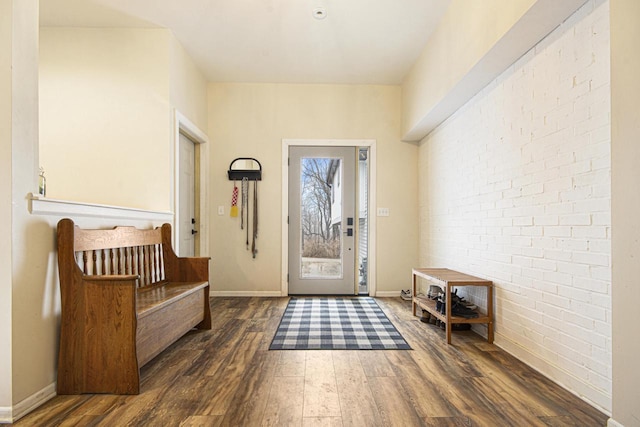 entryway with brick wall, baseboards, and hardwood / wood-style flooring