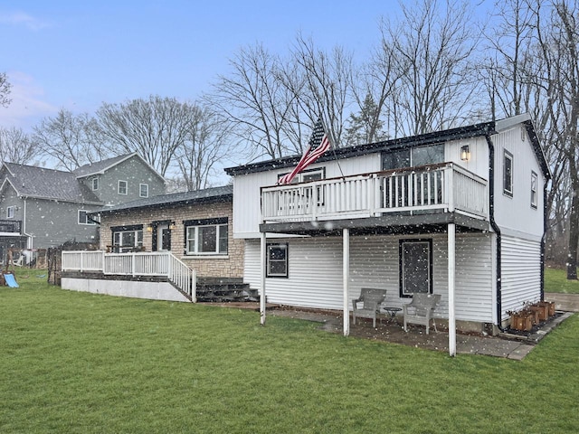 rear view of house with a deck, a yard, and stone siding