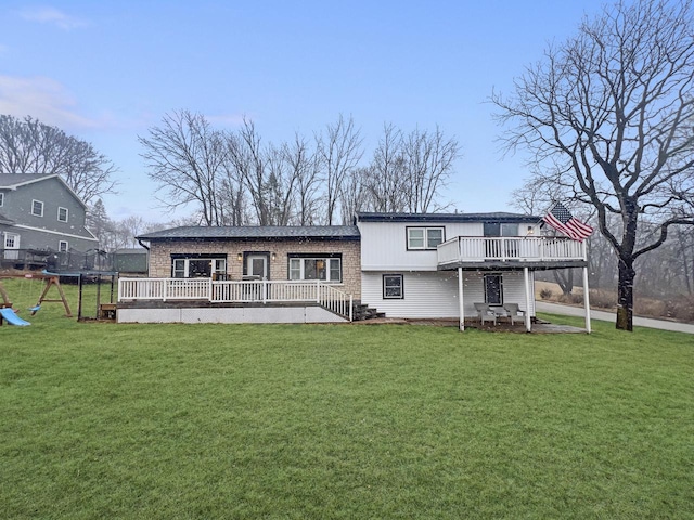 rear view of property featuring a yard, a playground, and a wooden deck