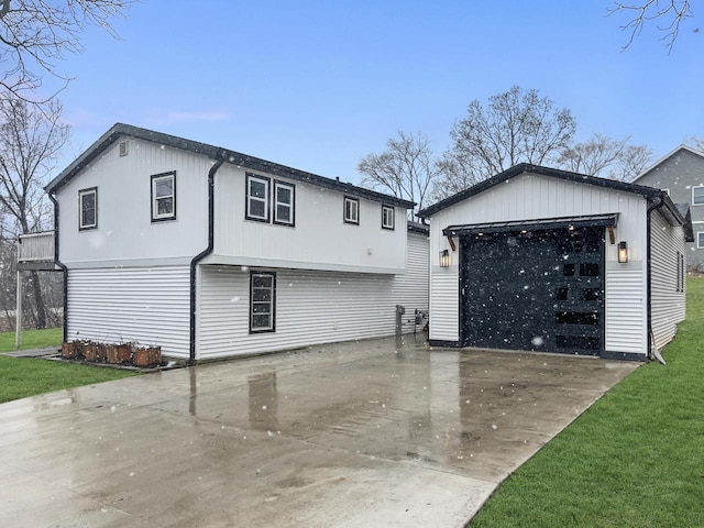 view of front of property with a front yard, an outdoor structure, and a detached garage