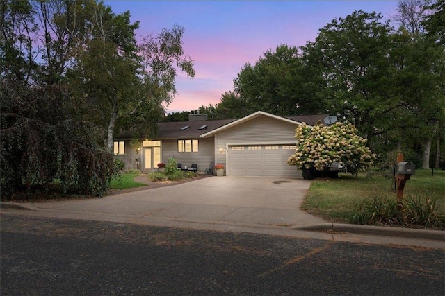 ranch-style home with a garage, driveway, and a chimney