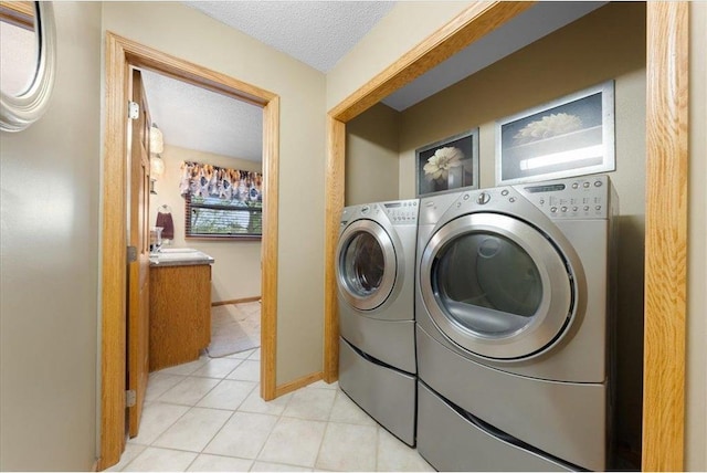 clothes washing area featuring a textured ceiling, light tile patterned floors, laundry area, baseboards, and independent washer and dryer