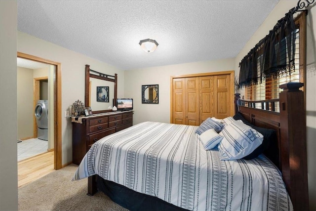 bedroom with a closet, washer / clothes dryer, light colored carpet, and a textured ceiling