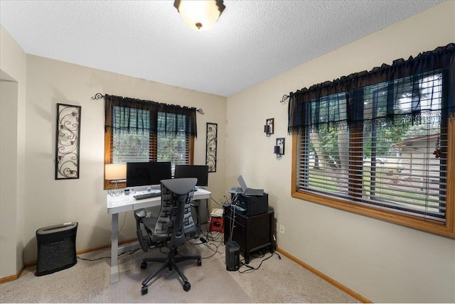 carpeted office space with a textured ceiling and baseboards