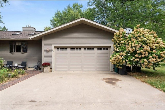 ranch-style home featuring a garage, a chimney, and concrete driveway