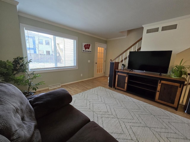 living room featuring wood finished floors, visible vents, baseboards, stairway, and crown molding