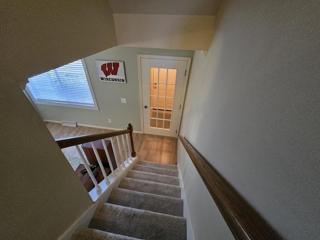 stairway featuring lofted ceiling, wood finished floors, and baseboards