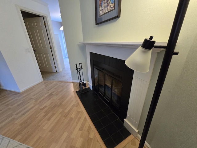 details with a tiled fireplace, wood finished floors, and baseboards