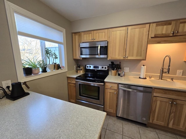 kitchen featuring appliances with stainless steel finishes, light countertops, a sink, and light tile patterned floors