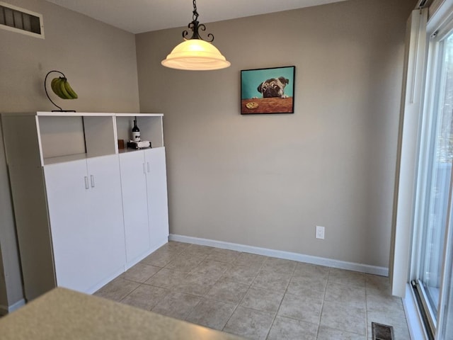 unfurnished room with light tile patterned floors, visible vents, and baseboards