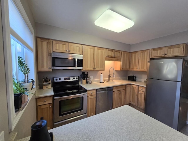 kitchen with appliances with stainless steel finishes, light countertops, and a sink