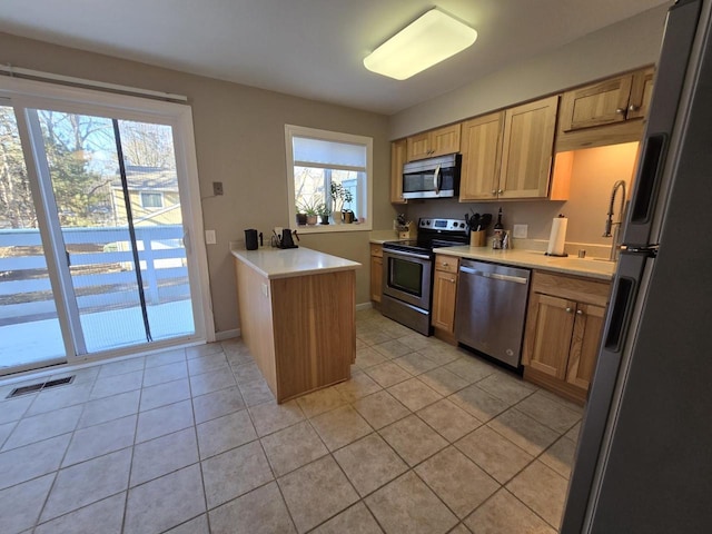 kitchen featuring stainless steel appliances, a wealth of natural light, light countertops, visible vents, and a peninsula