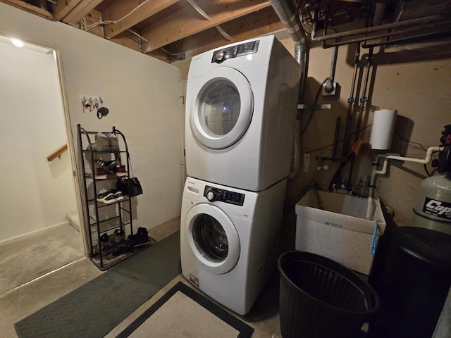 laundry area featuring stacked washing maching and dryer, laundry area, and a sink