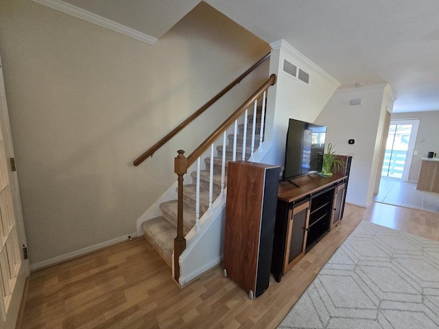 stairs featuring ornamental molding, visible vents, baseboards, and wood finished floors