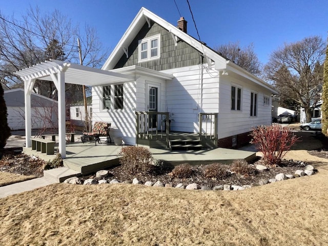 back of house featuring a chimney and a pergola