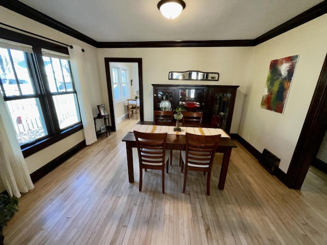 dining room with ornamental molding, wood-type flooring, and baseboards