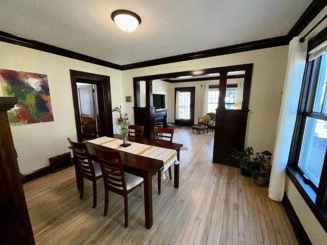 dining room with ornamental molding, light wood-style floors, and baseboards