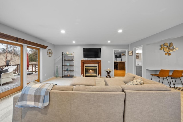 living room with a tile fireplace, light carpet, baseboards, and recessed lighting