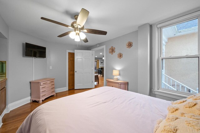 bedroom featuring ceiling fan, multiple windows, dark wood finished floors, and baseboards