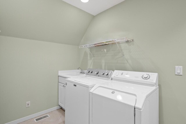 washroom featuring light tile patterned floors, separate washer and dryer, a sink, visible vents, and cabinet space