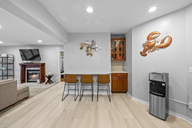 kitchen with tasteful backsplash, baseboards, a tile fireplace, brown cabinets, and recessed lighting