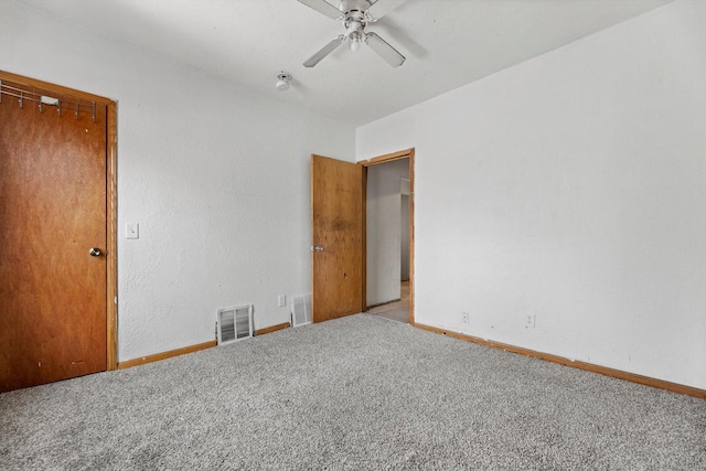 carpeted spare room featuring ceiling fan, visible vents, and baseboards