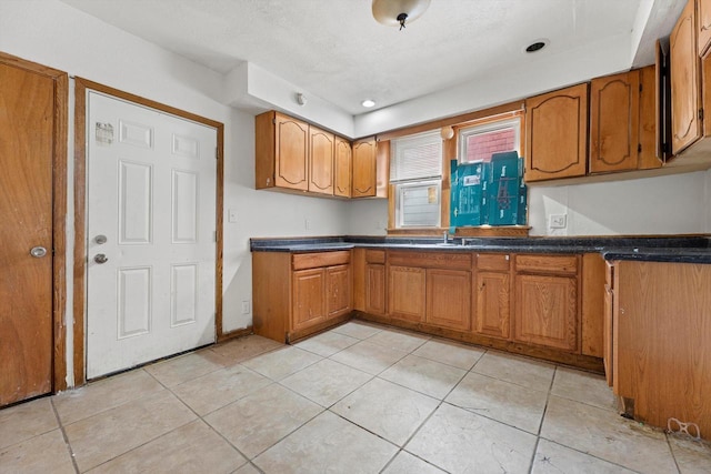 kitchen featuring dark countertops, light tile patterned floors, and brown cabinets