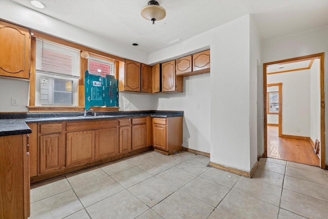 kitchen featuring brown cabinetry, dark countertops, plenty of natural light, and light tile patterned floors