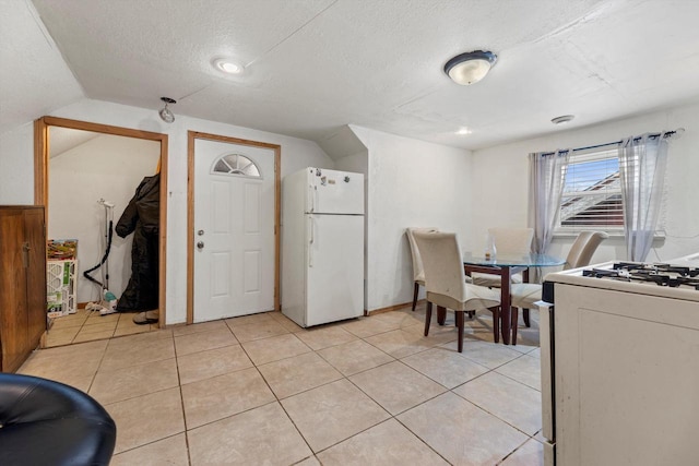 dining room with vaulted ceiling, a textured ceiling, and light tile patterned floors