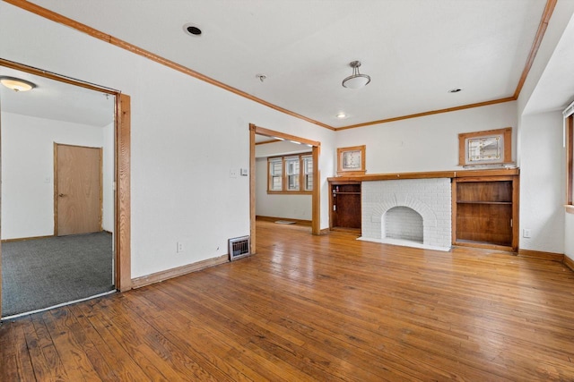 unfurnished living room with a fireplace, visible vents, baseboards, hardwood / wood-style floors, and crown molding