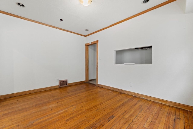 empty room with baseboards, visible vents, crown molding, and hardwood / wood-style floors