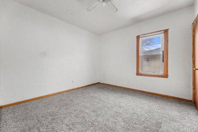 carpeted empty room featuring a ceiling fan and baseboards