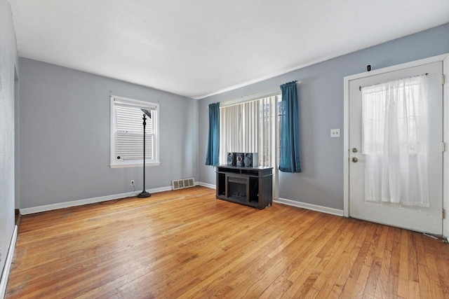 unfurnished living room featuring light wood-style flooring, visible vents, and baseboards