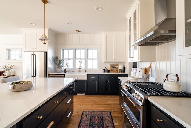 kitchen with a sink, dark cabinetry, wall chimney range hood, and stainless steel appliances