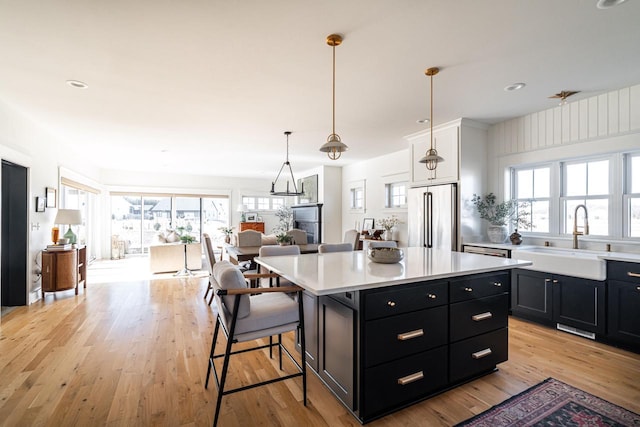 kitchen with a sink, light countertops, dark cabinets, and high end refrigerator