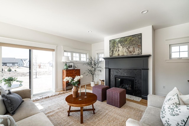 living area with recessed lighting, a premium fireplace, baseboards, and light wood-style flooring