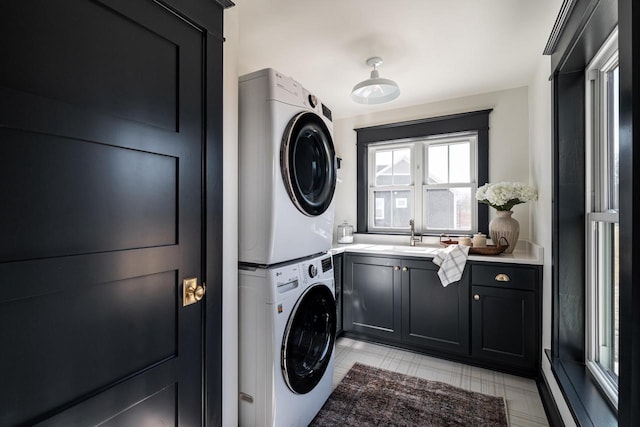 washroom featuring a sink, cabinet space, and stacked washing maching and dryer