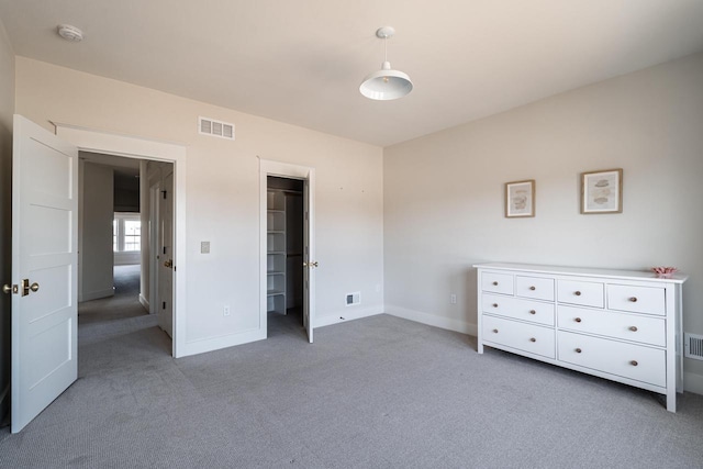 unfurnished bedroom featuring a spacious closet, carpet, visible vents, and baseboards