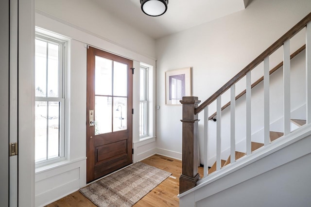 entryway featuring light wood-type flooring, baseboards, and stairs