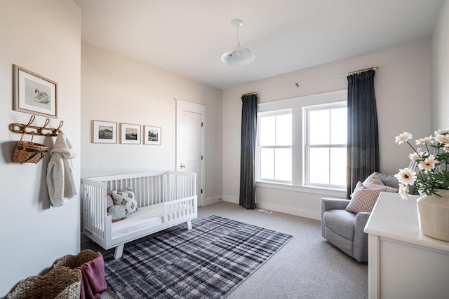 bedroom with baseboards, carpet floors, visible vents, and a crib