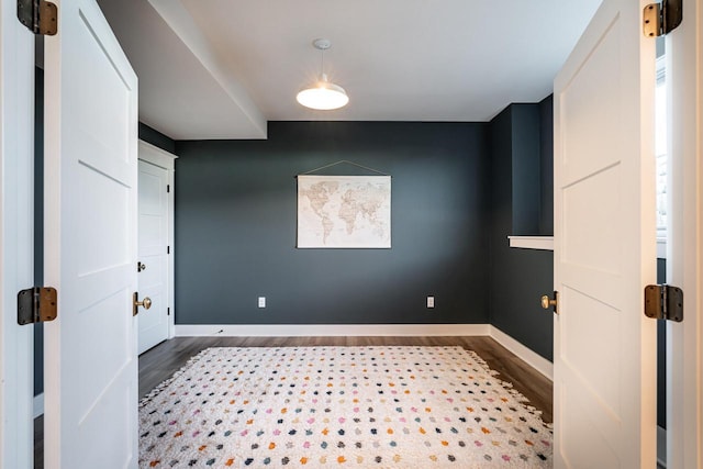 empty room featuring a barn door, wood finished floors, and baseboards