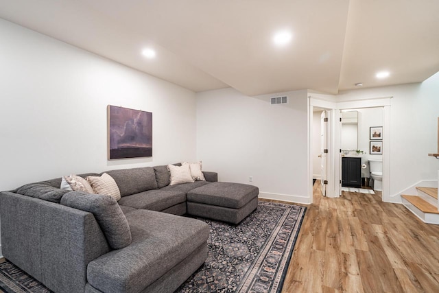 living area featuring baseboards, visible vents, light wood-style flooring, recessed lighting, and stairs