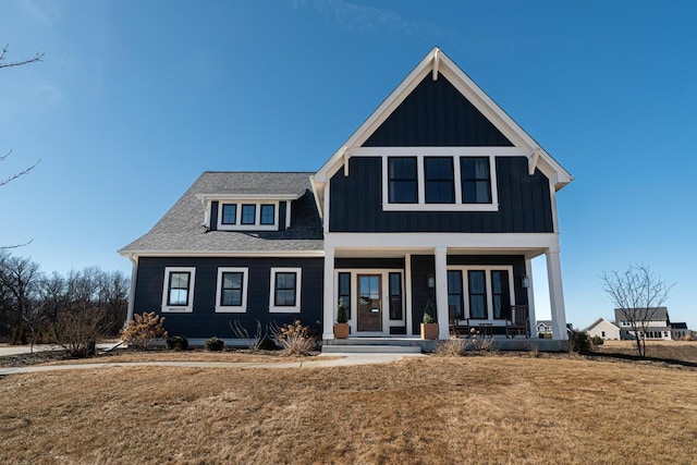 view of front facade featuring a porch, board and batten siding, a front yard, and a shingled roof