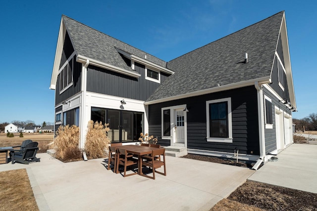 back of house with a garage, a patio, and a shingled roof