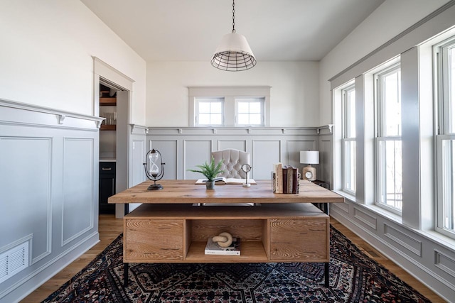 office area featuring a decorative wall, visible vents, and a wealth of natural light